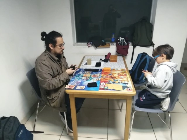 Un adulto y un niño jugando Pokémon TCG en una mesa del local