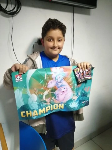 Jugador nuevo con su playmat de campeón tras un torneo de Pokémon en el local